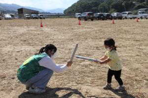 チャンバラゲームで向かい合う小さな子と学生