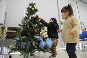 クリスマスツリーに触る二人の子供の写真