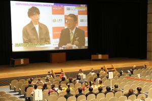 市長と実行委員のビデオメッセージが映されている会場の様子の写真