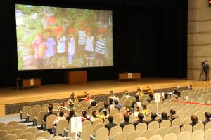 小中学校の思い出がスクリーンに映る会場の様子