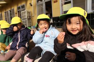 黄色い帽子の園児たちが繭玉を食べている様子の写真