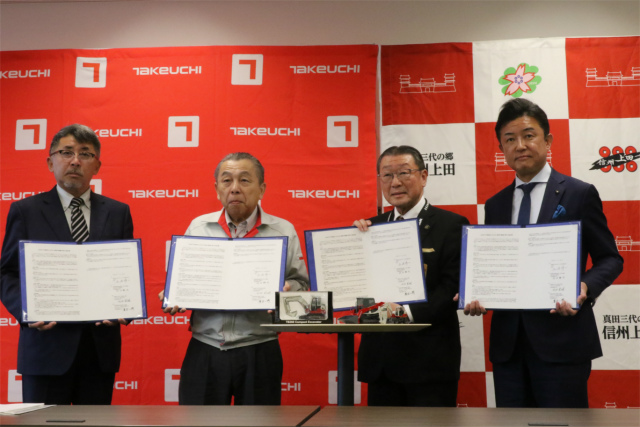 協定締結式の様子（４者代表が協定書を持って並んでいる）