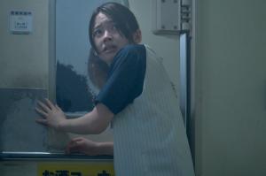 『夜勤事件』のメインビジュアル。壁に片手を添えて、怯えた表情で背後を振り返っている。