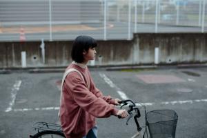 『遠くへいきたいわ』のメインビジュアル。自転車を押している女性。
